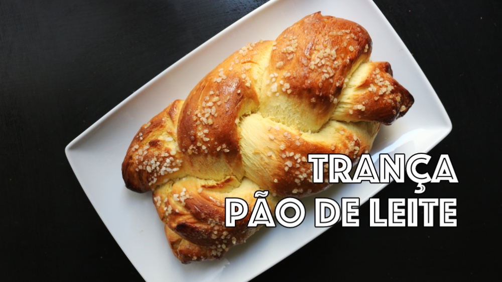 pão de leite em formato de trança num prato branco sobre mesa preta